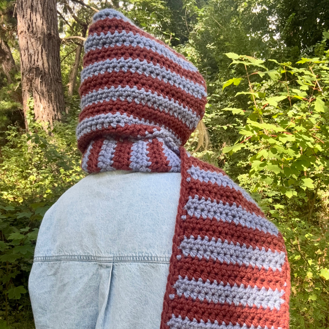 Person wearing a brown and blue striped scarf in a forest setting