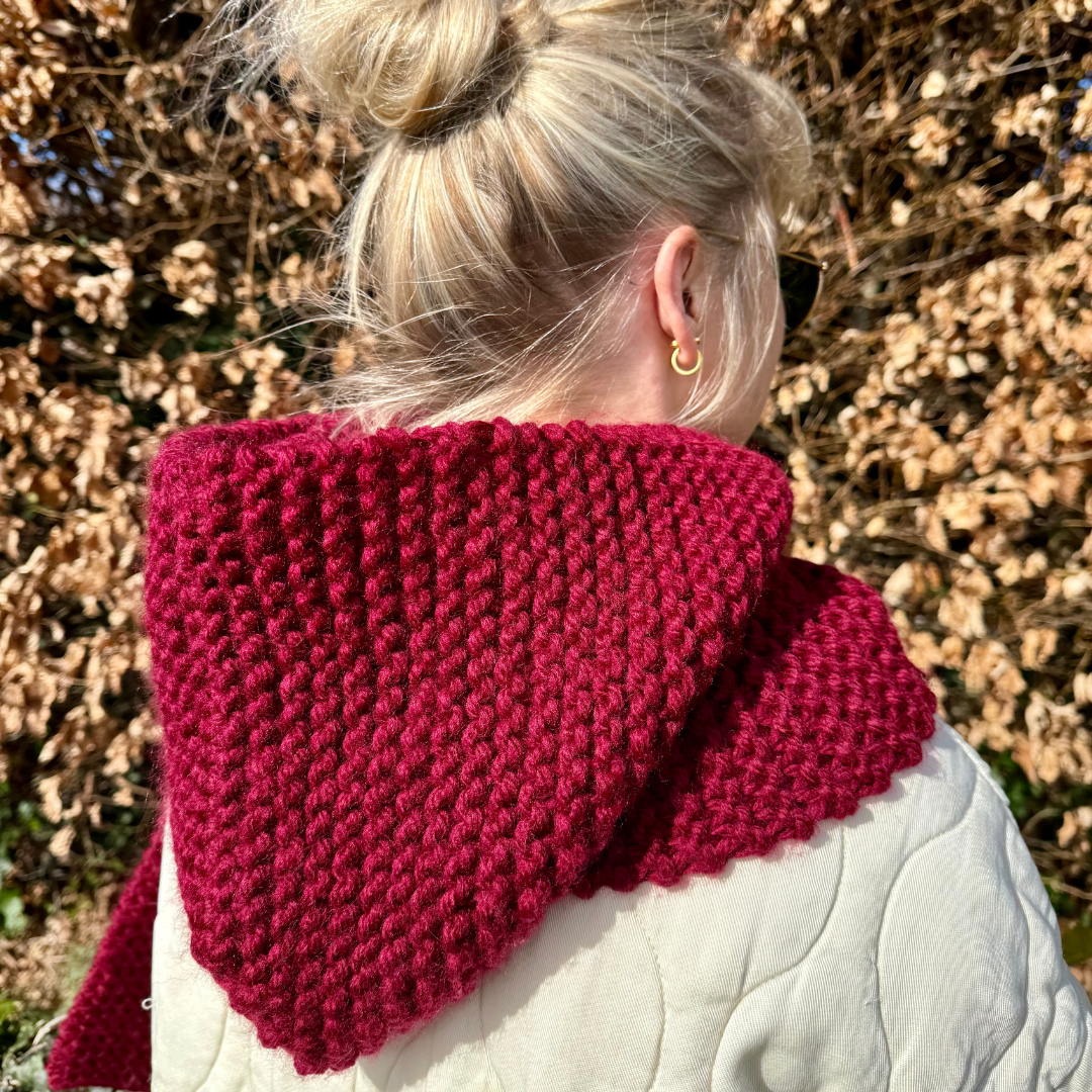 Person wearing a red knitted scarf with a blurred natural background