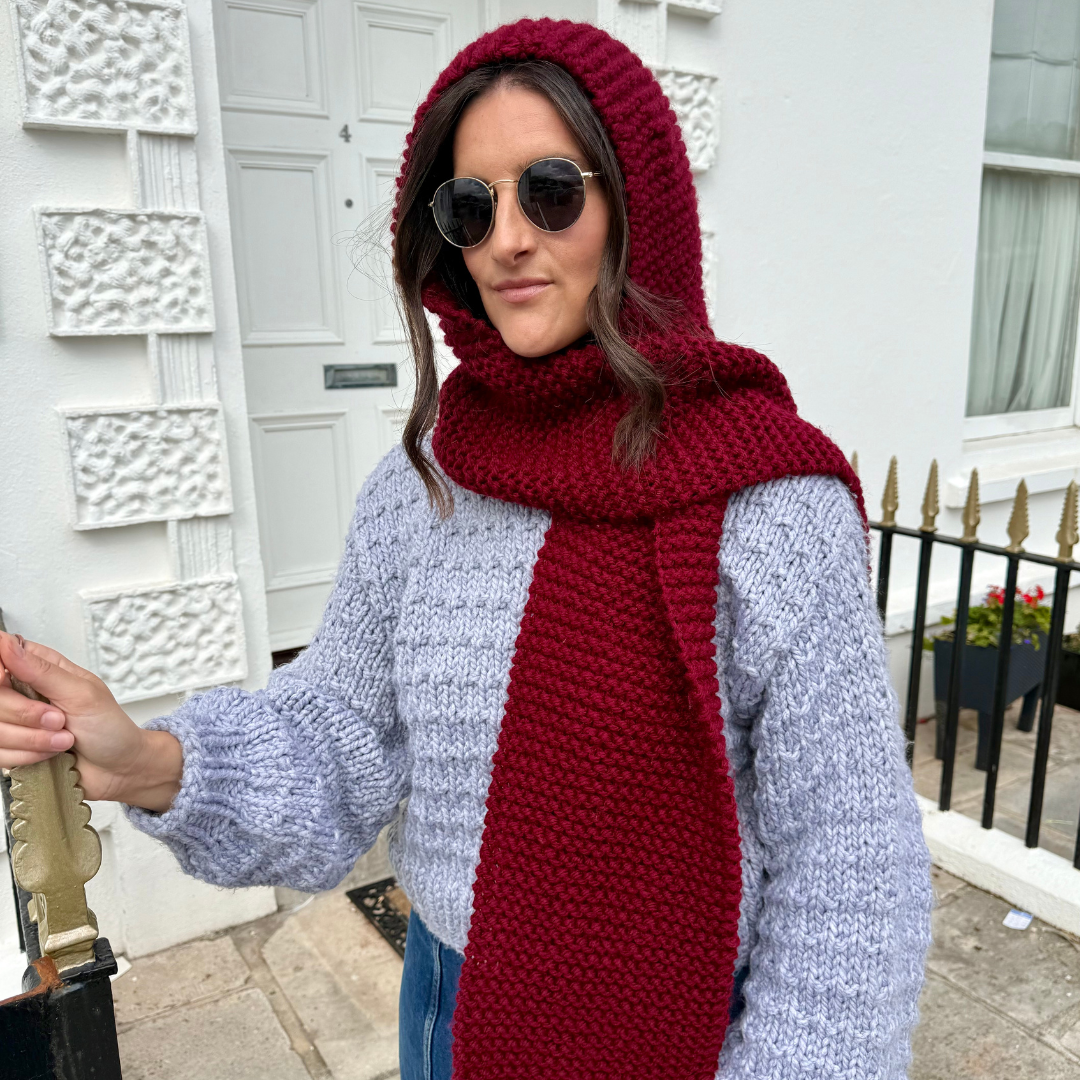 Woman wearing a red knitted hood and scarf in an urban setting