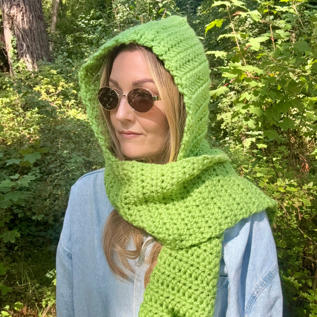 Person wearing a green knitted hood in a forest setting