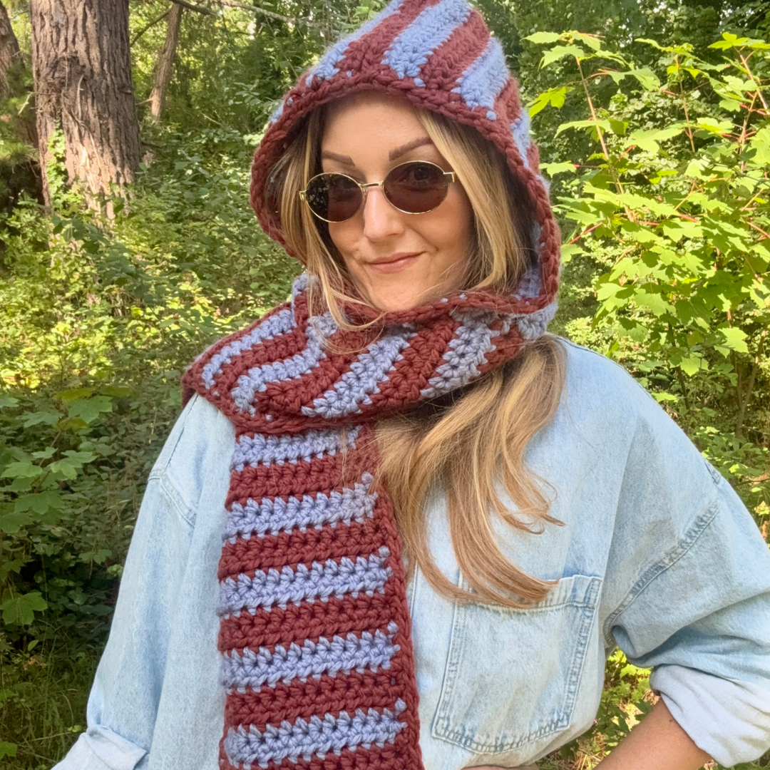 Person wearing a striped hood and scarf in a forest setting