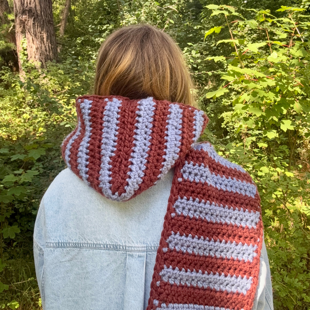 Person wearing a brown and blue striped scarf in a forest setting