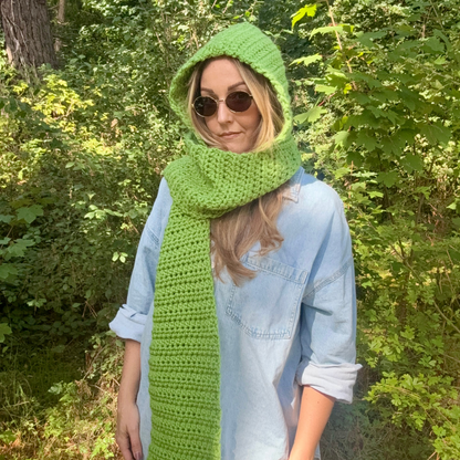 Person wearing a green hood and scarf standing in a forest