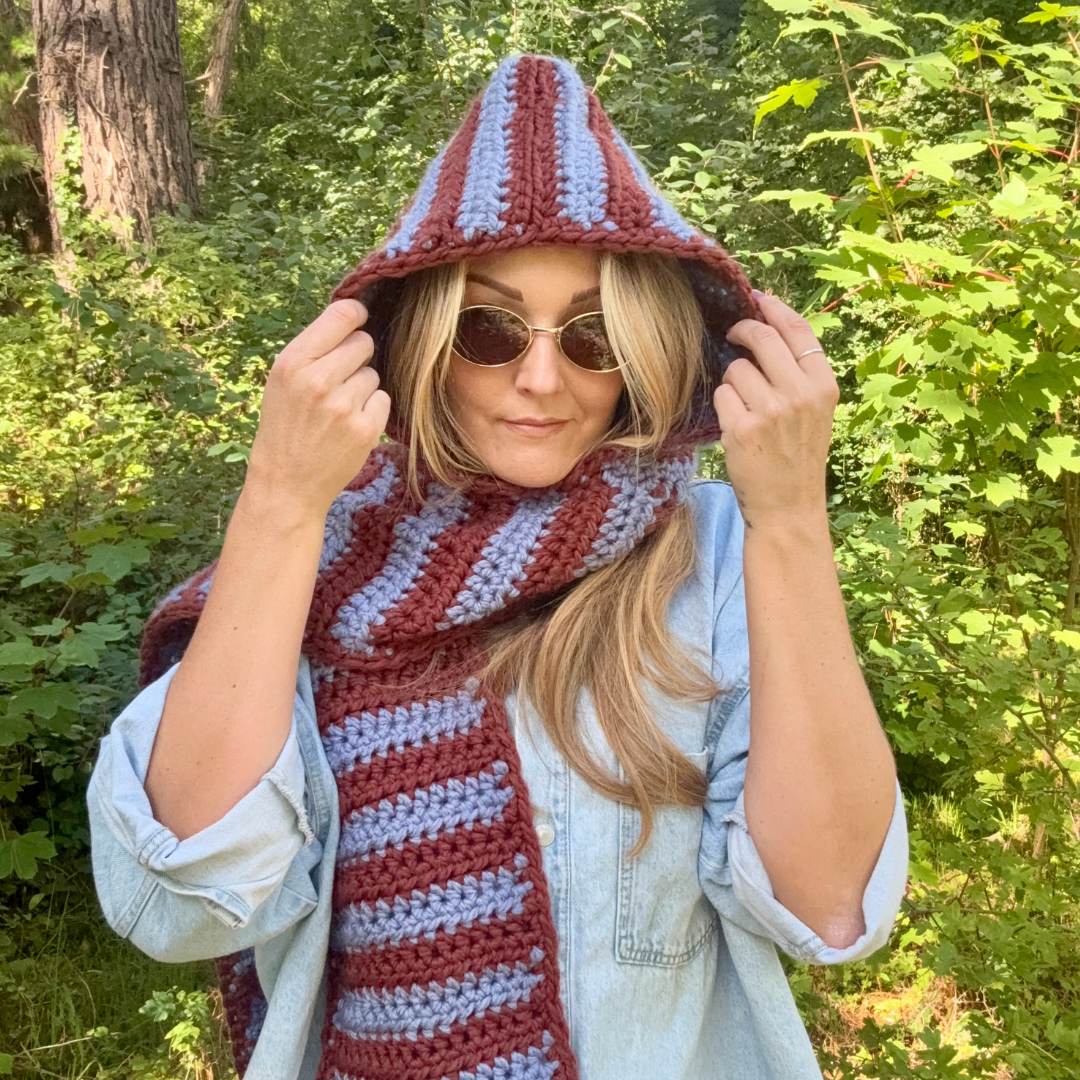 Person wearing a striped hooded scarf in a forest setting
