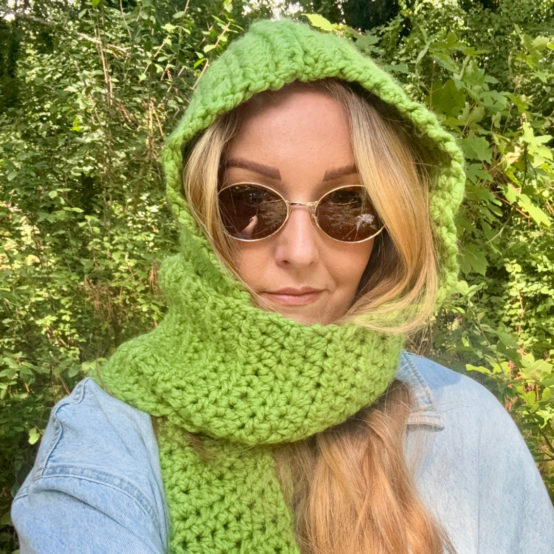 Person wearing a green knitted hood and scarf outdoors