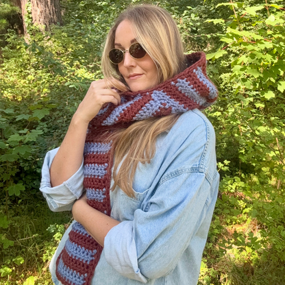 Woman wearing a colorful striped crochet scarf in a forest setting