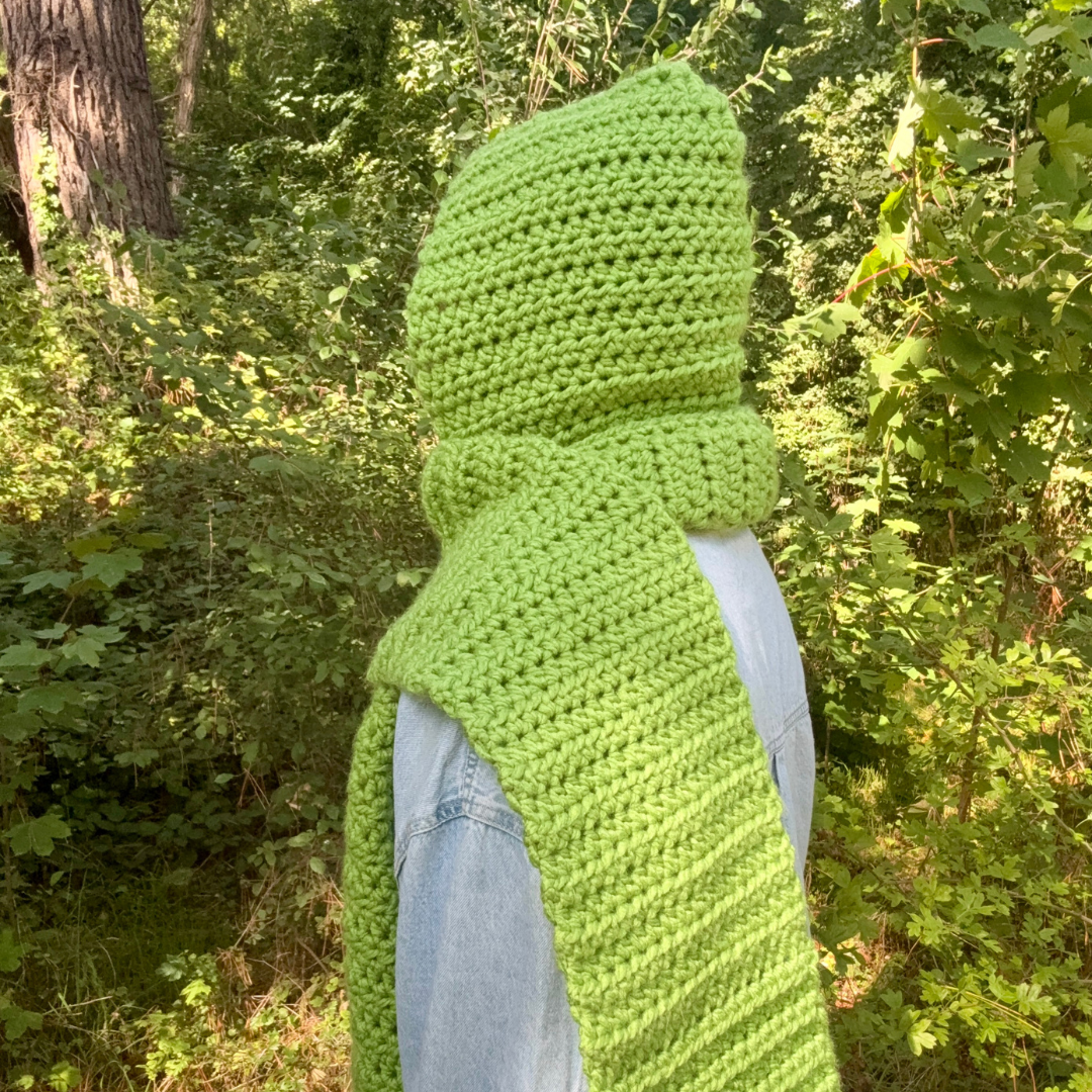 Person wearing a green knitted hood in a forest setting