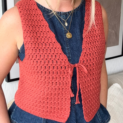 Person wearing a red crochet vest over a blue denim shirt.